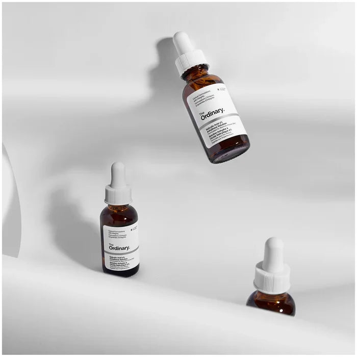 Three bottles of 'The Ordinary' serum on a light gray background