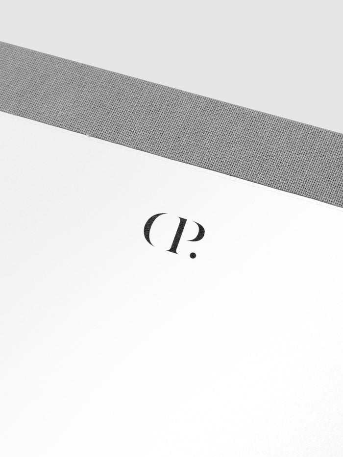 Closeup of notepad's Cloth and Paper logo header and gray fabric spine.