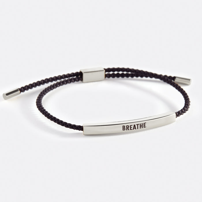 A two-tone inspirational tube bracelet with the word 'BREATHE' printed on it, displayed on a white background with the word 'breathe' also written there.