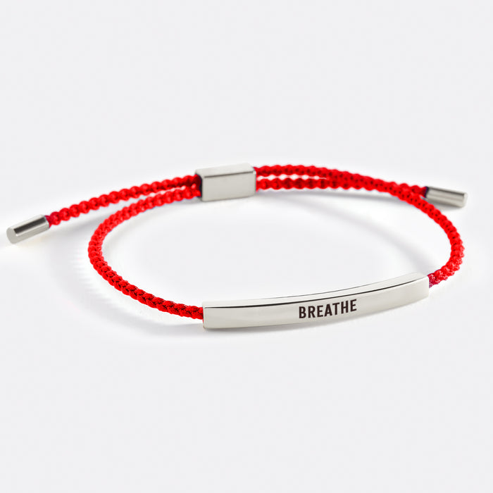 A two-tone inspirational tube bracelet with the word 'BREATHE' printed on it, displayed on a white background with the word 'breathe' also written there.