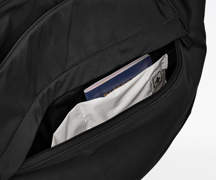 Black backpack with a pocket open, revealing a white shirt and blue notebook inside.