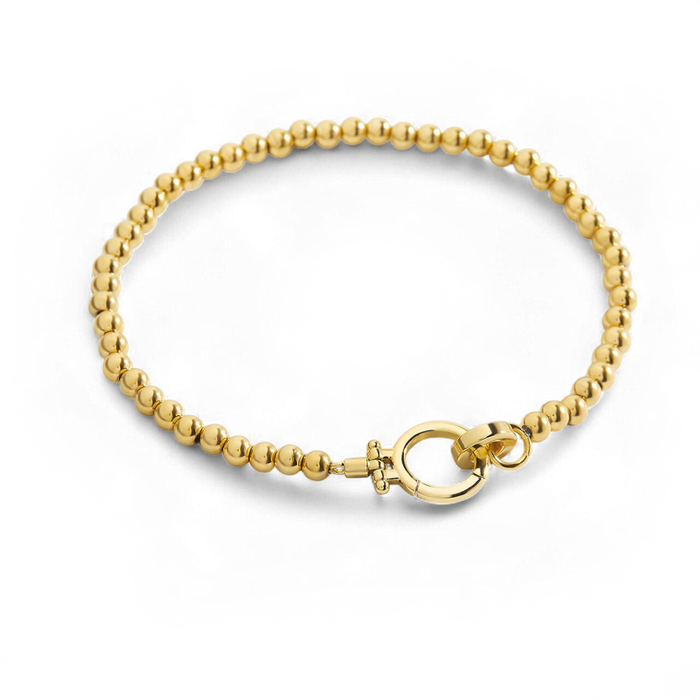 A gold-colored beaded bracelet with a mint green charm clasp, displayed against a black background.