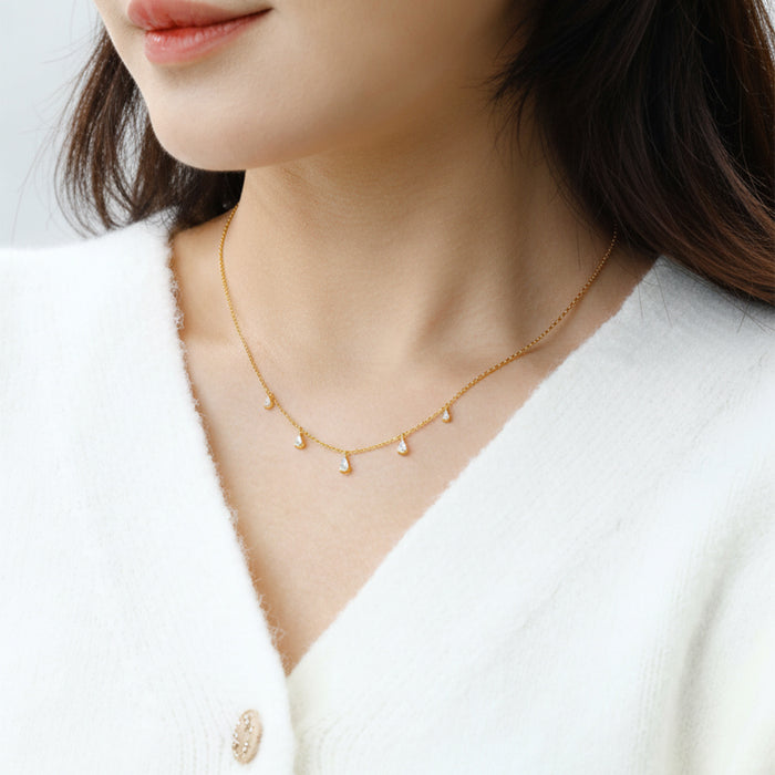 Gold necklace worn by a person against a white background