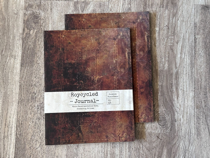 A close up view of two Roycycled Treausures Art Journals rustic dark brown distressed covers on wood background