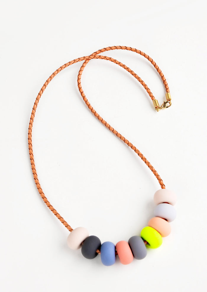 Woven leather cord necklace with gold clasp and rounded clay beads tans, pinks,gray, blue, and neon yellow.
