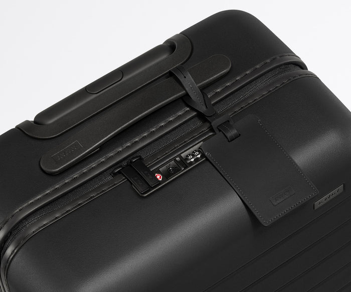 The leather luggage tag on top of a matching Away suitcase